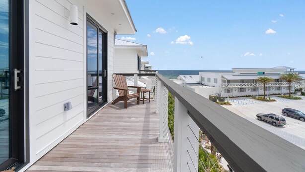 A modern building with a wooden deck, a covered outdoor seating area, and a view of the ocean and other buildings. - The Bluffs #6 - Coastal Bliss (Orange Beach)