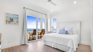 Ein Schlafzimmer mit einem großen Bett, einem Deckenventilator und Meerblick durch eine Schiebetür.