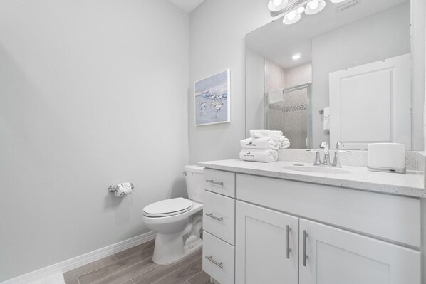Een moderne badkamer met toilet, wastafel en spiegel.