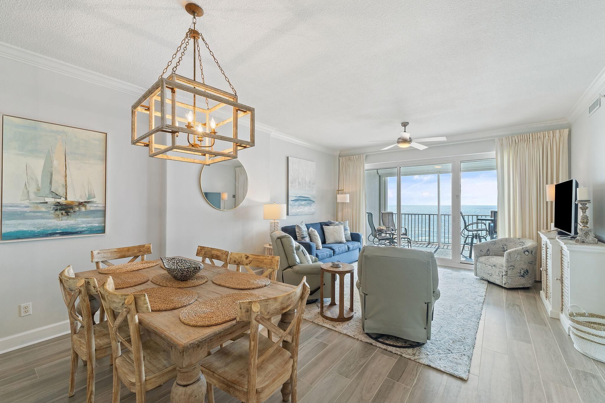 A spacious living room with a dining area, a large window with a view, and a ceiling fan.
