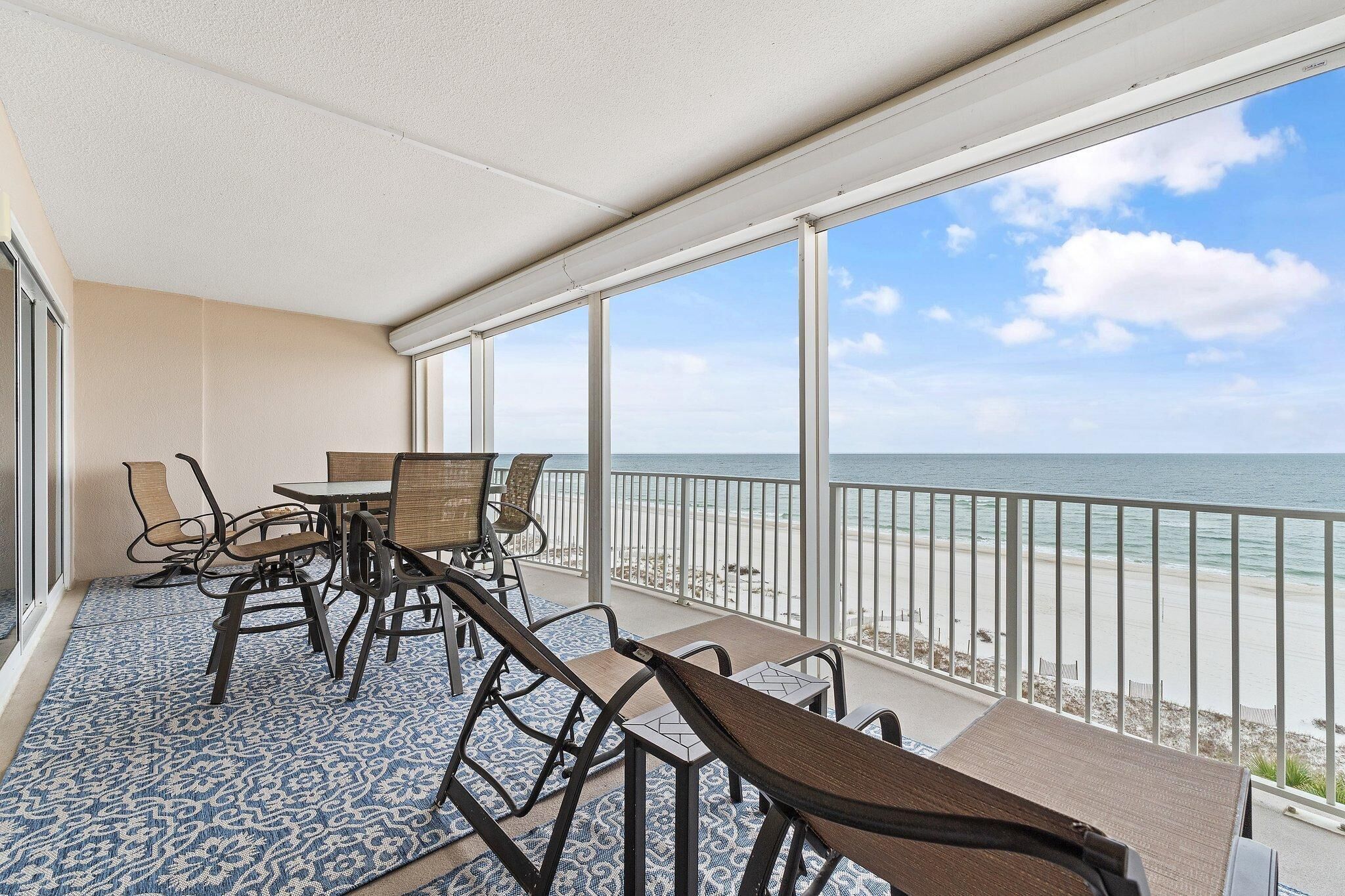 Ein Balkon mit Blick auf den Strand, ausgestattet mit Stühlen und einem Tisch.