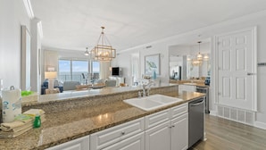 A modern kitchen with granite countertops, white cabinetry, and a large island with a sink.