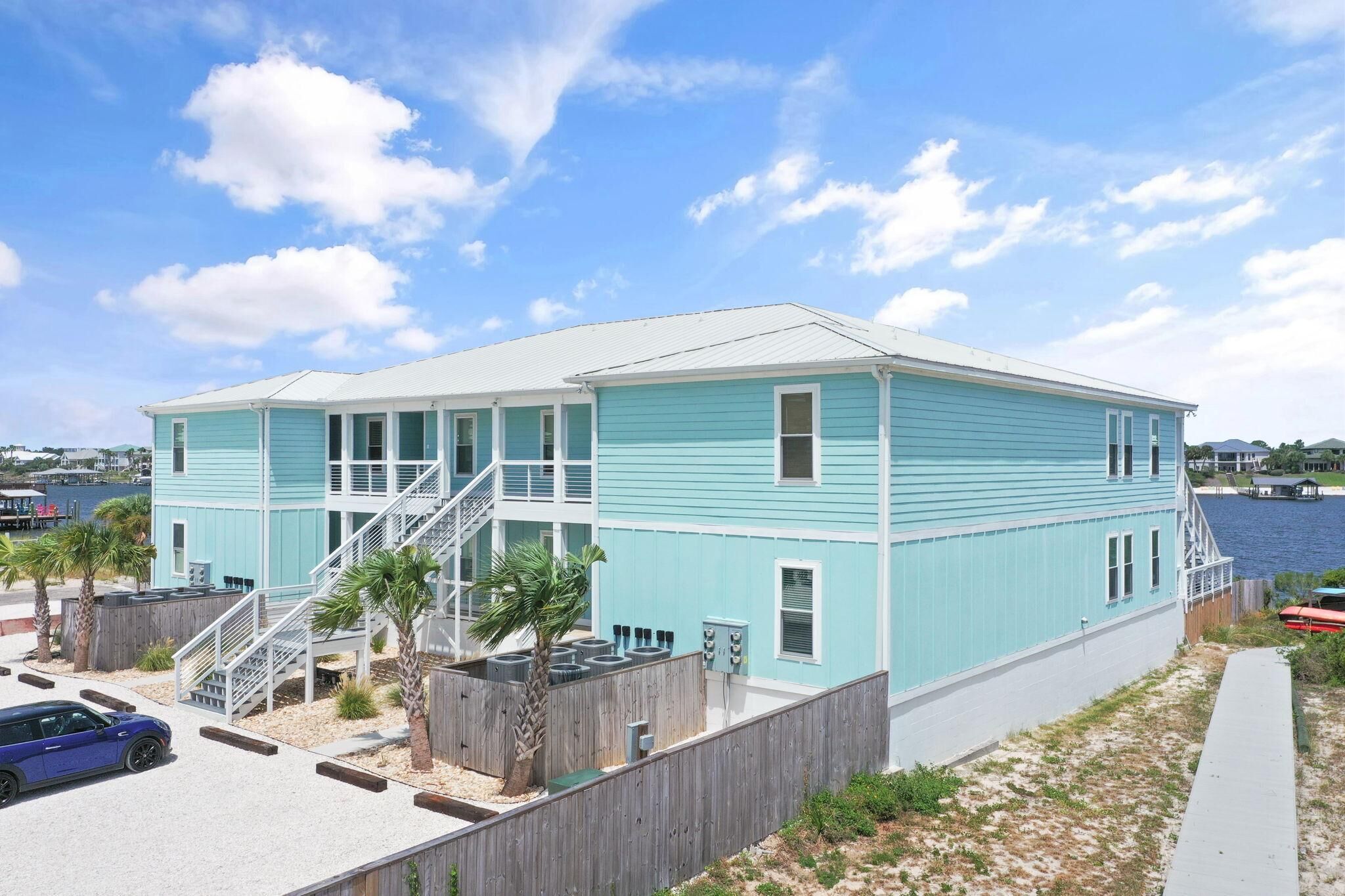 A two-story house with a white roof, blue siding, and a wooden deck.