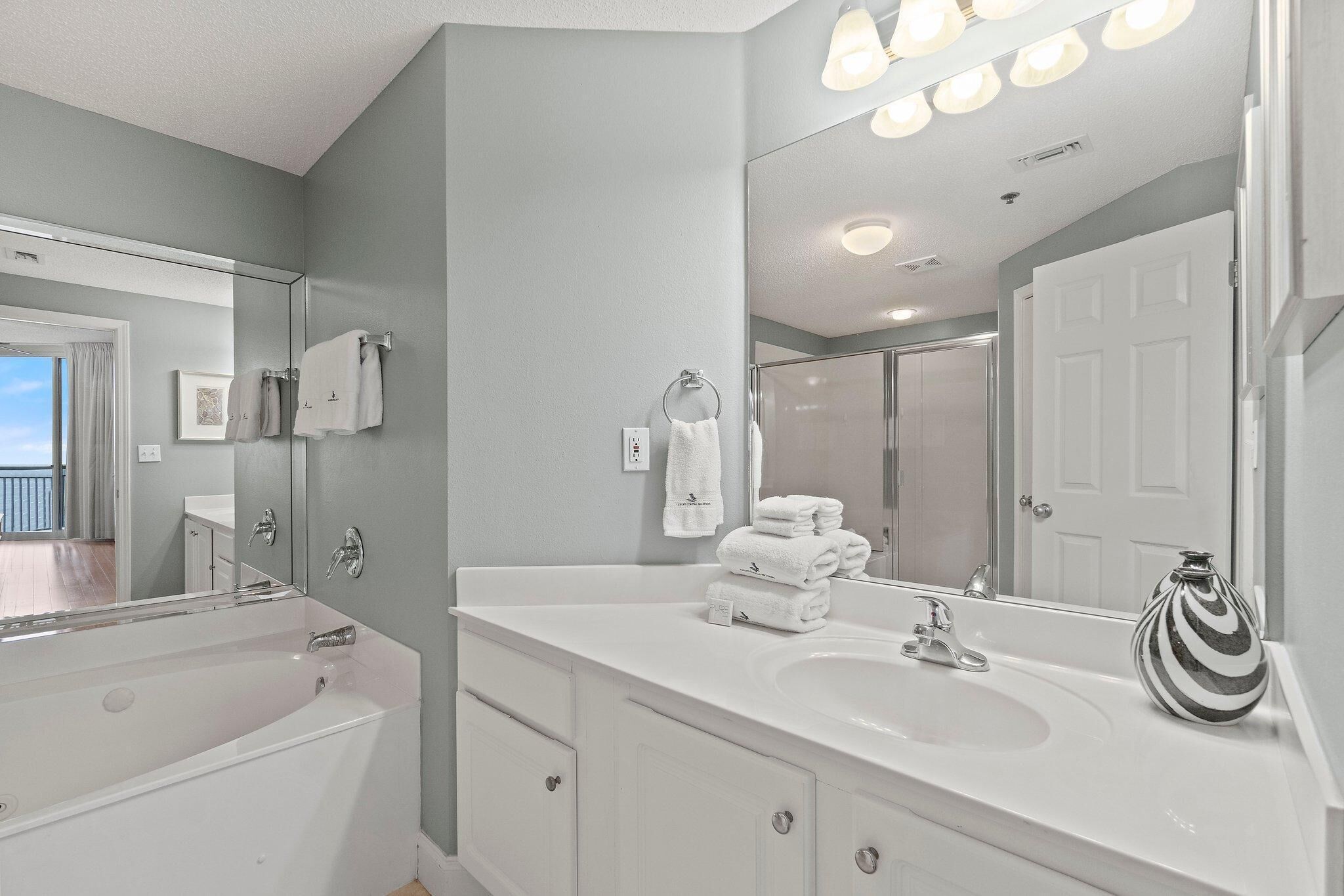 A modern bathroom with a large mirror, two sinks, and a bathtub.