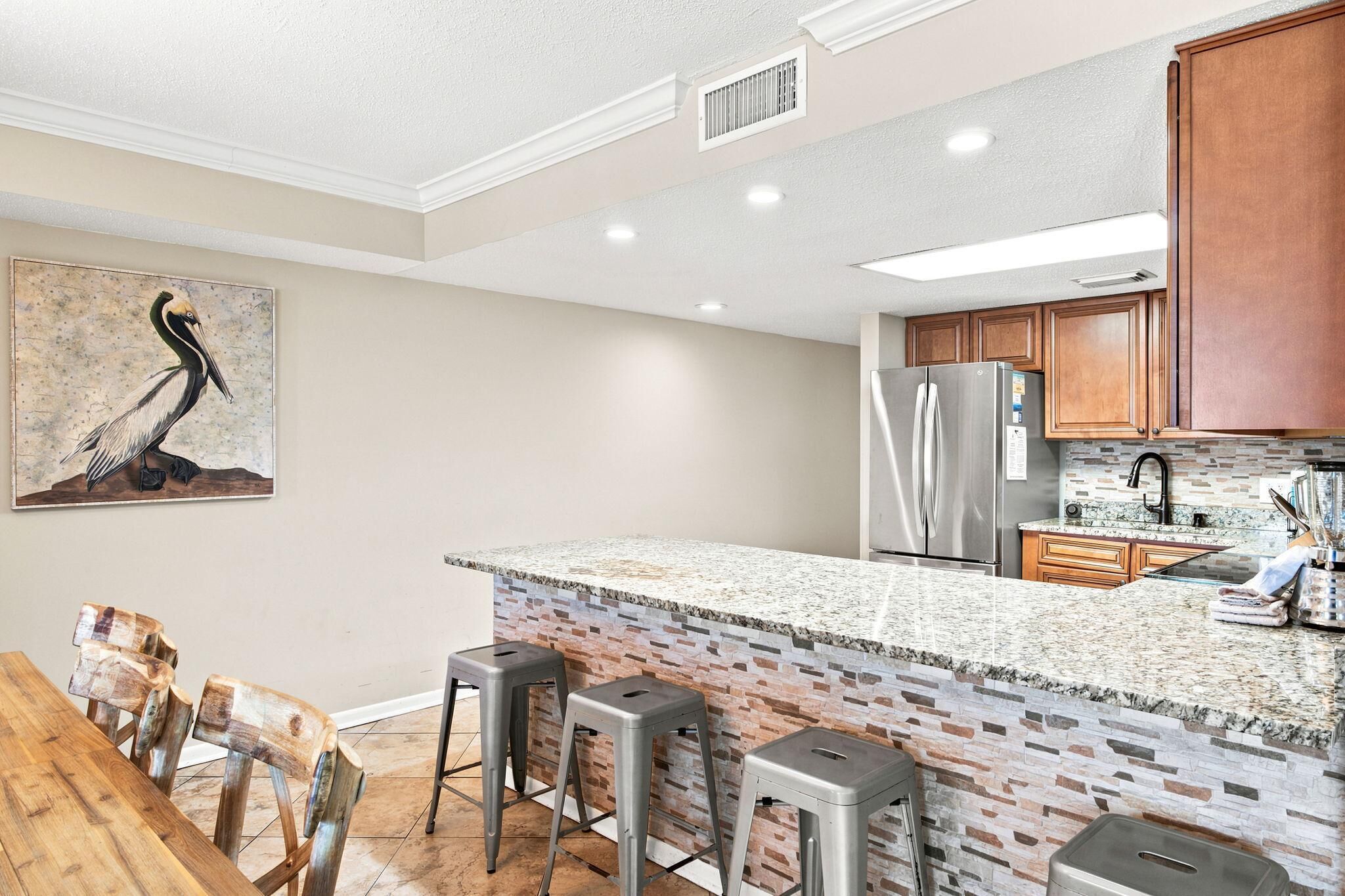 A kitchen with a granite countertop, stainless steel appliances, and a brick backsplash.