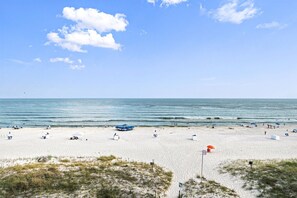 A beach with white sand, a few umbrellas, and a clear sky. - Castaways 5D (Gulf Shores)