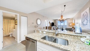 A kitchen with granite countertops, stainless steel sink, and a chandelier. - Windemere 602 (Pensacola)