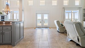 A spacious living area with a large window, a kitchen with granite countertops, and a seating area with two chairs. - Lime In The Coconut (Gulf Shores)