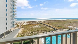 Een hotel met een zwembad, uitzicht op het strand en een pier.