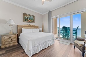 Relax in this serene retreat with a large bed, nightstand, and lamp, plus a sliding door to an outdoor area with ocean views.
