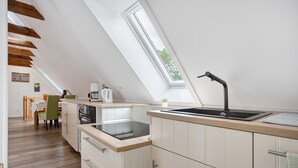 Een moderne keuken met een dakraam, houten balken en uitzicht op de omgeving.