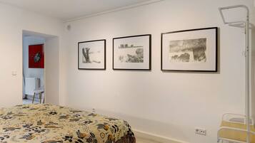 A bedroom with a bed, a chair, and three framed pictures on the wall.