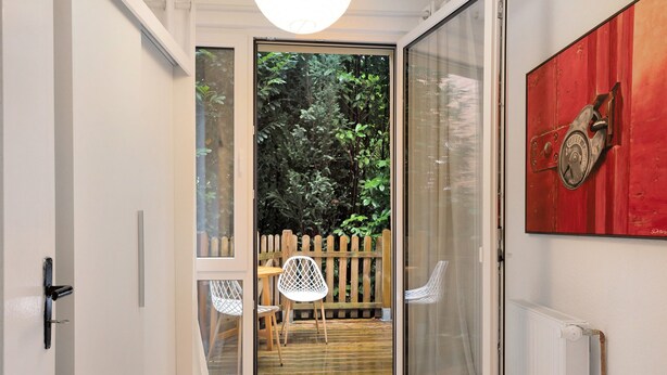 Quarto com porta de vidro deslizante que dá para área externa com deck de madeira e cadeiras.