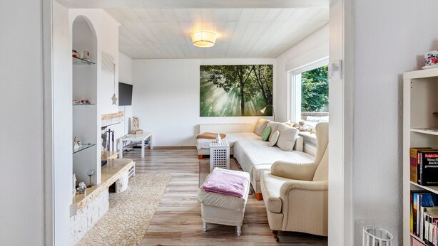 Een gezellige woonkamer met een bank, een bijzettafeltje en een boekenplank.