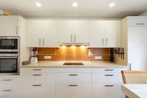 Eine moderne Küche mit weißen Schränken, einem Backofen, einem Mixer und einem Spülbecken.