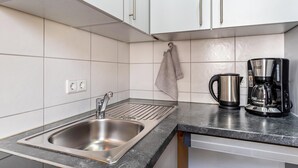 A kitchen with a stainless steel sink, a coffee maker, and a towel hanging on the wall. - Studio Apartment 'Ferienwohnung Lehen - Herr 1' with Shared Garden and Wi-Fi (Freiburg im Breisgau)