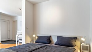 A bedroom with a bed, two bedside tables, a chair, and a desk. - Studio Apartment 'Ferienwohnung Lehen - Herr 1' with Shared Garden and Wi-Fi (Freiburg im Breisgau)