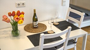A dining table with a bottle of wine, two glasses, and a vase of tulips. - Studio Apartment 'Ferienwohnung Lehen - Herr 1' with Shared Garden and Wi-Fi (Freiburg im Breisgau)