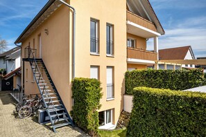 A multi-story building with a staircase, a balcony, and a hedge.