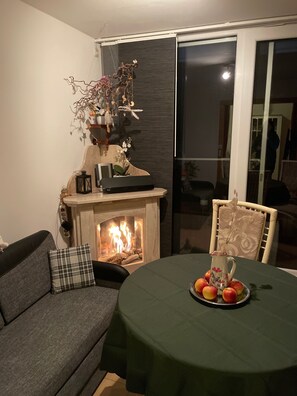 Una sala de estar con chimenea, un sofá, una mesa con fruta y un adorno en la pared.
