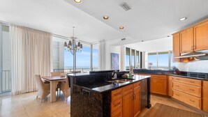 Une cuisine moderne dotée d’un grand îlot central, de meubles en bois et offrant une vue sur l’extérieur.