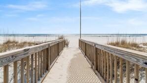 Une promenade en bois menant à une plage, avec un ciel dégagé.
