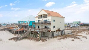 Il s'agit d'une propriété située en bord de mer, comprenant plusieurs bâtiments, notamment une maison à deux étages dotée d'un balcon et une construction plus petite avec un toit bleu.