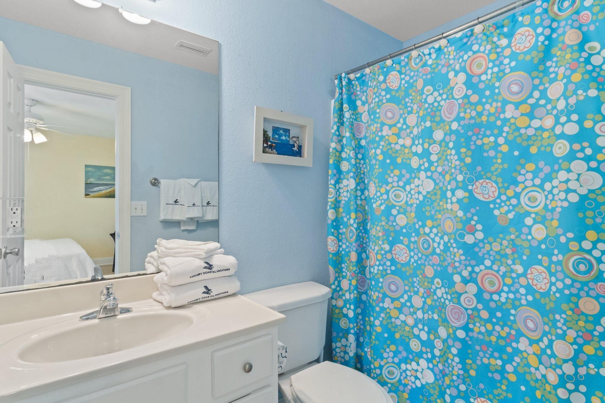A bathroom with a sink, toilet, and a shower curtain with a floral pattern.
