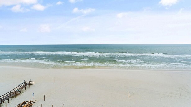 Een strand met een houten pier die zich uitstrekt over de oceaan.