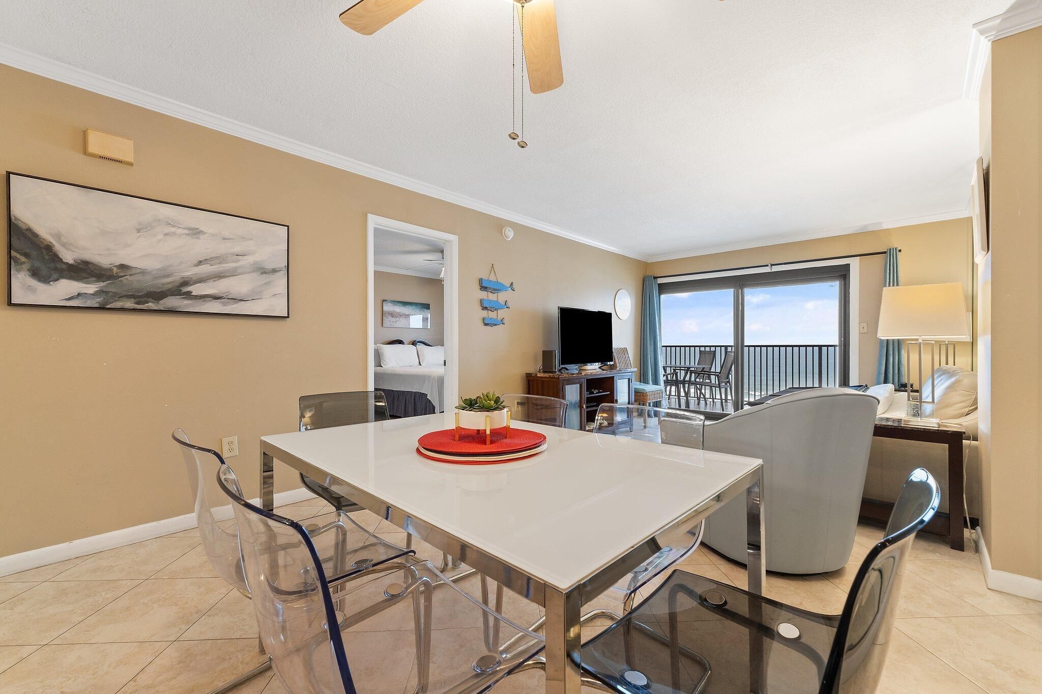 A modern living room with a dining area, a TV, and a balcony with a view.