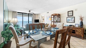 A dining area with a glass table, wicker chairs, and a view of the ocean. - Summerchase 506 (Orange Beach)