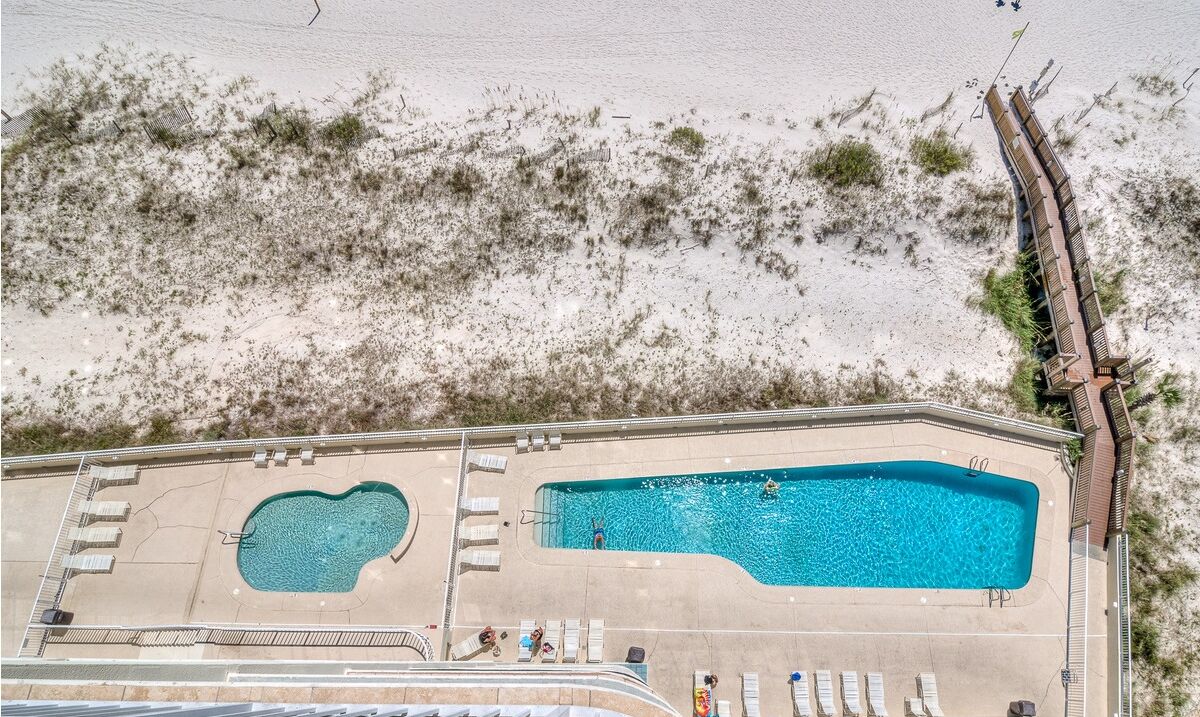 A pool area with two pools, sun loungers, and a deck.