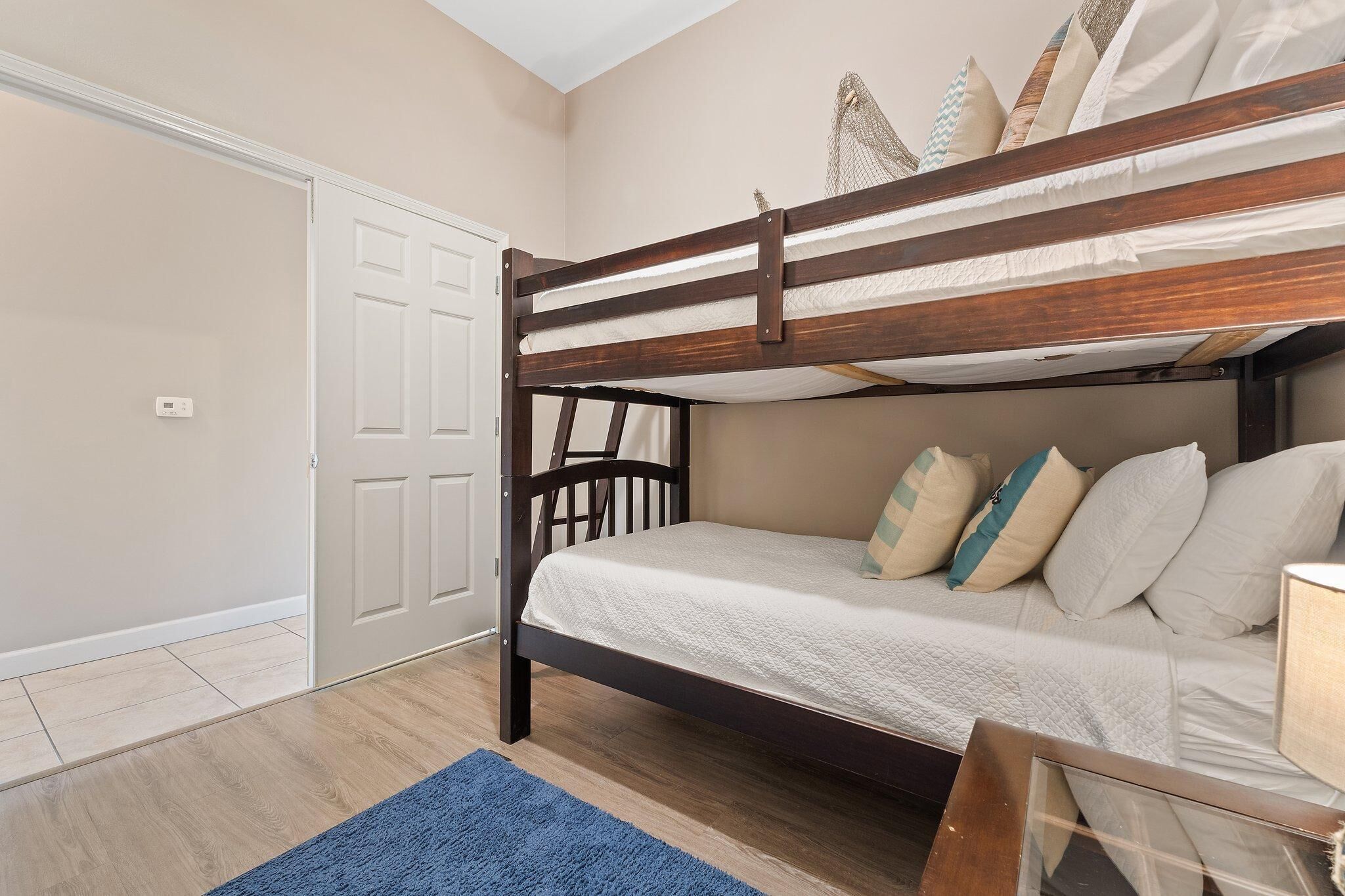A bunk bed with a wooden frame, white bedding, and decorative pillows.