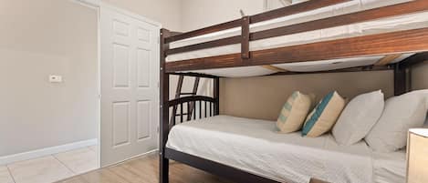 A bunk bed with a wooden frame, white bedding, and decorative pillows.
