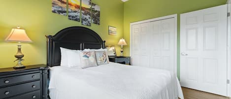 A bedroom with a bed, two nightstands, a dresser, and a door.