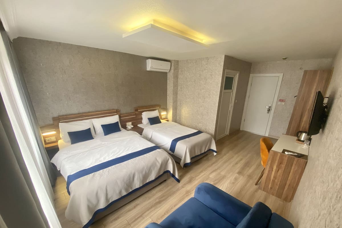 Une chambre d’hôtel avec deux lits, un bureau, une chaise et une télévision.