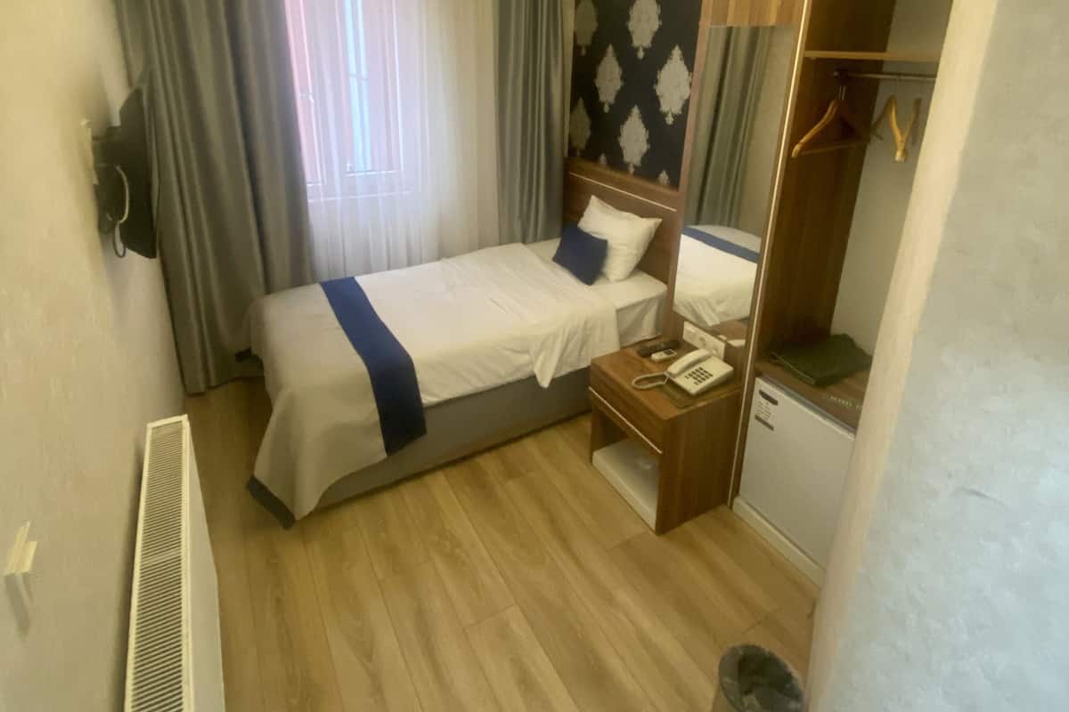 Une chambre d’hôtel avec un lit, une table de chevet et une armoire.