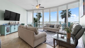 A spacious living room with a large TV, two sofas, a coffee table, and a ceiling fan. - Caribe C104 (Orange Beach)