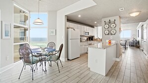 A spacious kitchen with a large island, white cabinetry, and a view to the outside. - Palacio 801 (Pensacola)