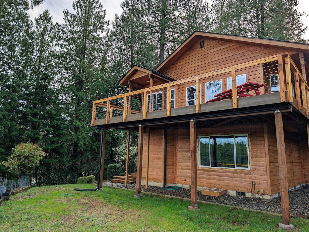 Une cabane en bois à deux étages, dotée d’un balcon et entourée d’une forêt.