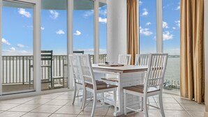 A balcony with a table and chairs, a view of the water, and a railing.