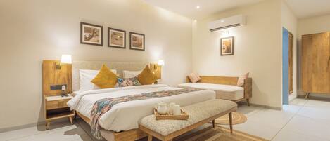 A hotel room with two beds, a wooden bench, a tray with toiletries, and a large window.