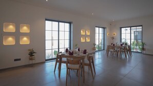 Un comedor espacioso con amplios ventanales, iluminación moderna y mobiliario de madera.