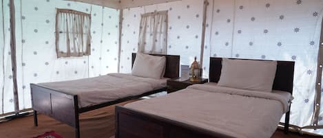 A room with two beds, a nightstand, a lamp, and a patterned rug.
