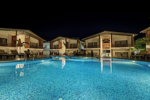 A swimming pool with a tiled surface, surrounded by buildings with balconies and outdoor seating areas.