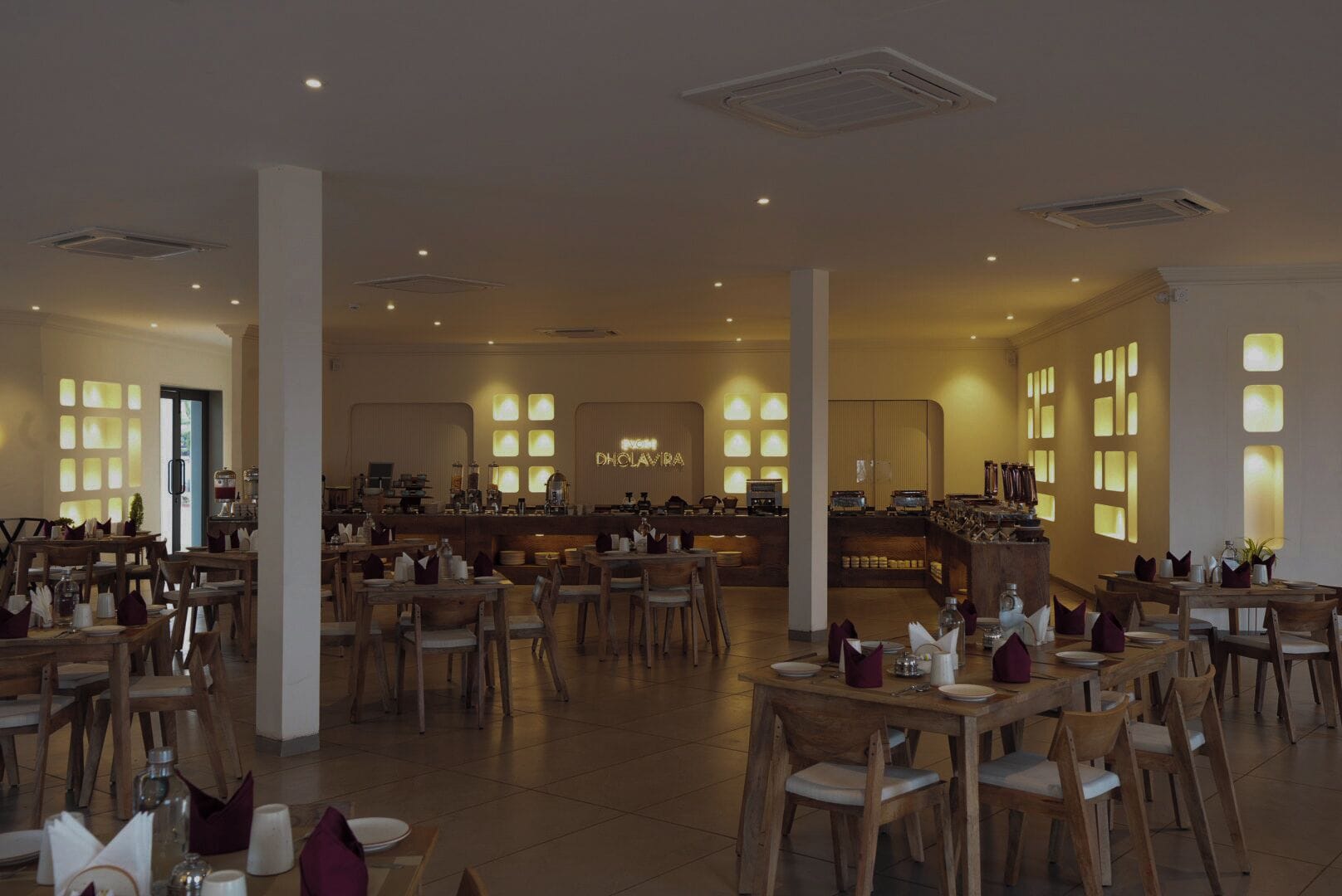 A spacious restaurant with multiple tables and chairs, a bar area, and a neon sign on the wall.