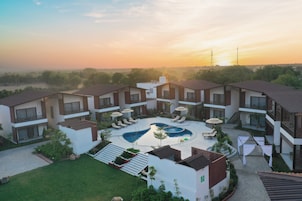 A modern hotel with a central swimming pool, multiple balconies, and a landscaped garden.