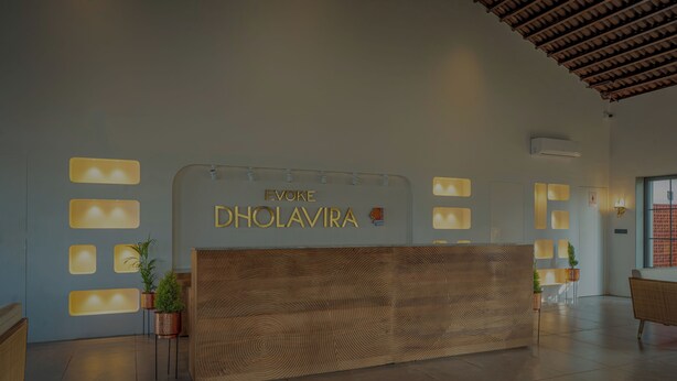 Un mostrador de recepción con terminación de madera y un letrero que dice 'Evoke Dholavira'.
