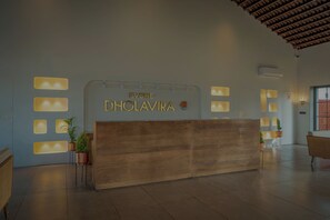 A reception desk with a wooden finish and a sign that reads "Evoke Dholavira".