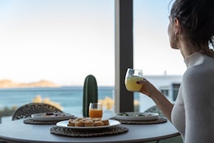Una persona sentada a una mesa con un plato de comida, un vaso de jugo de naranja y un cactus al fondo.